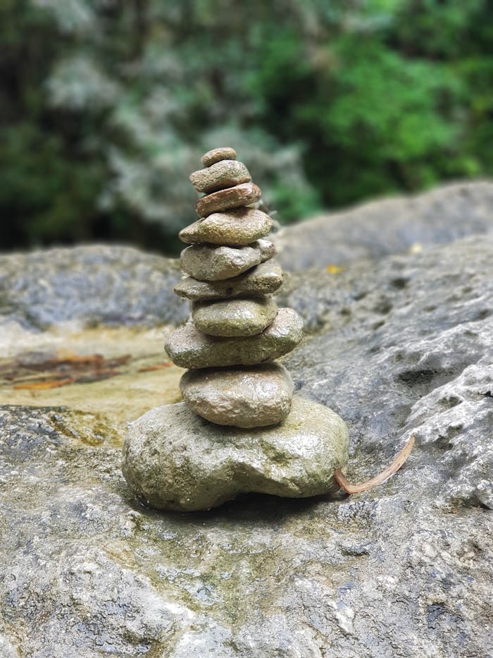The Art of Drawing Readers In: Your attractive post title goes here A harmonious stack of pebbles balanced on a rock surface in a lush outdoor setting.